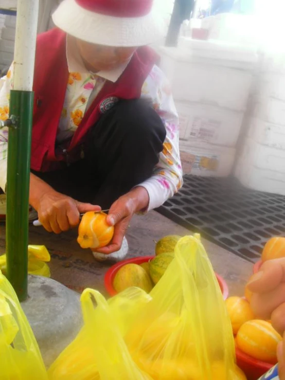 a young person in a white hat is peeling soing with a knife