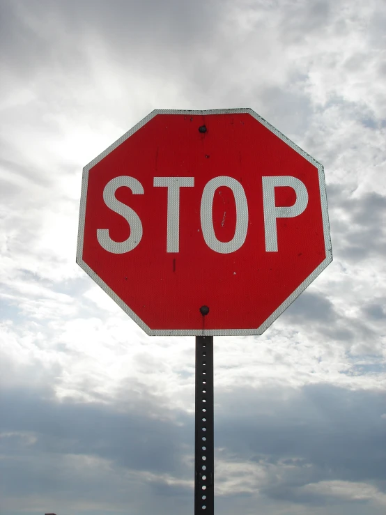 a close up of a stop sign with clouds in the background