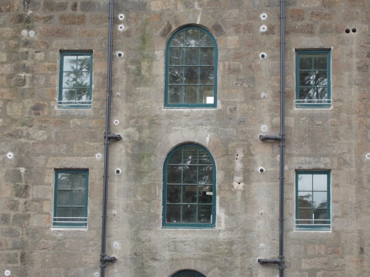 three windows and a bench are in front of an old building