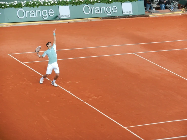 a tennis player has his arms in the air while he serves the ball