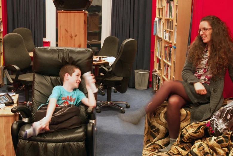 a woman and boy playing in a leather chair