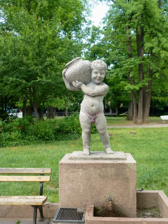 statue of a boy carrying an umbrella in park