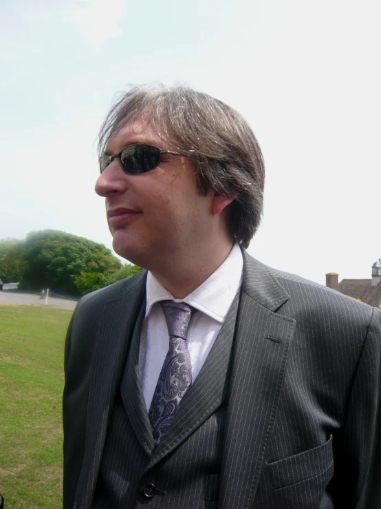 a man wearing a suit and tie in a field