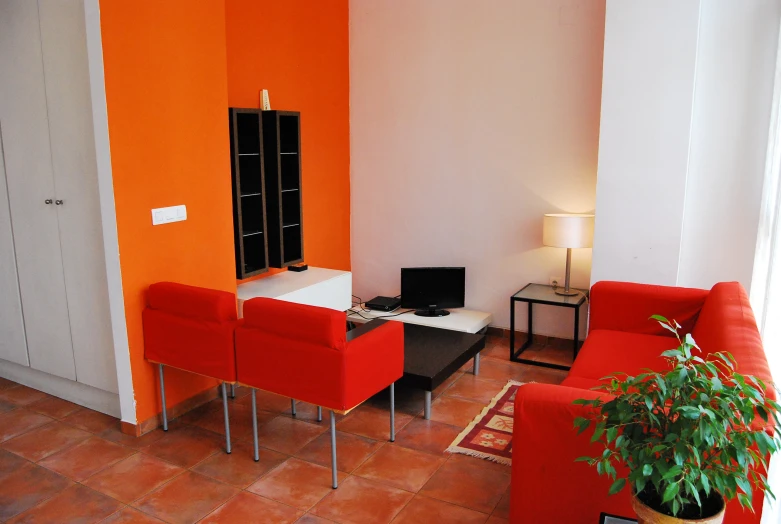 an orange living room features two red chairs, an ottoman, a black table with a lamp and two lamps