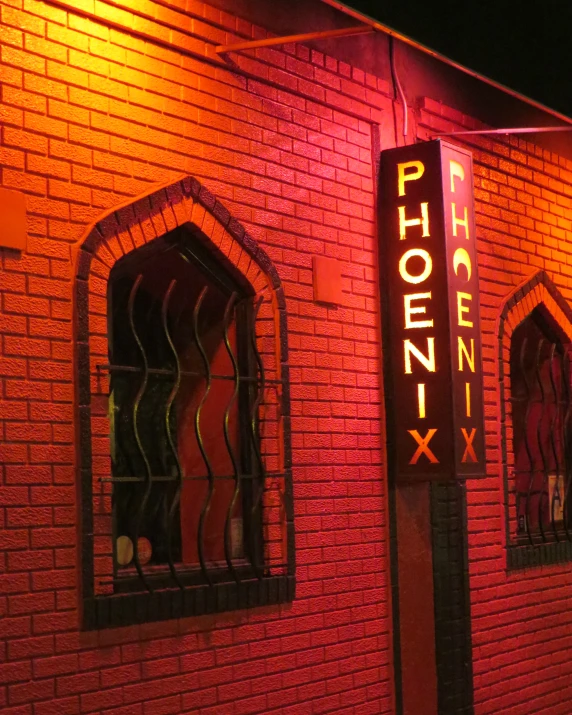 a tall brick building with a neon sign outside