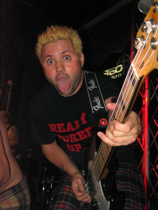 a man with blonde hair is holding a guitar