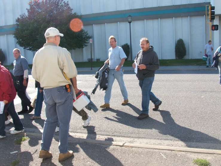 several men are walking in the street while carrying items