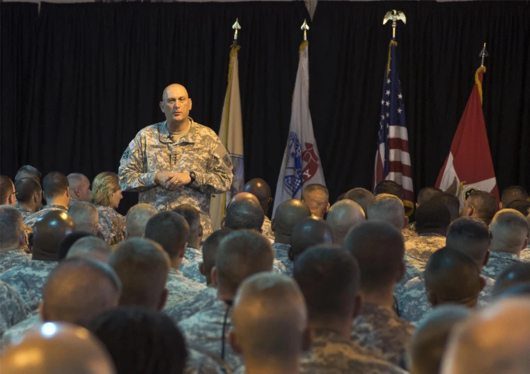 two military men sitting next to each other on military uniforms in front of flags