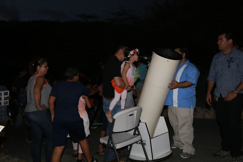 a group of people gathered together next to a tall object