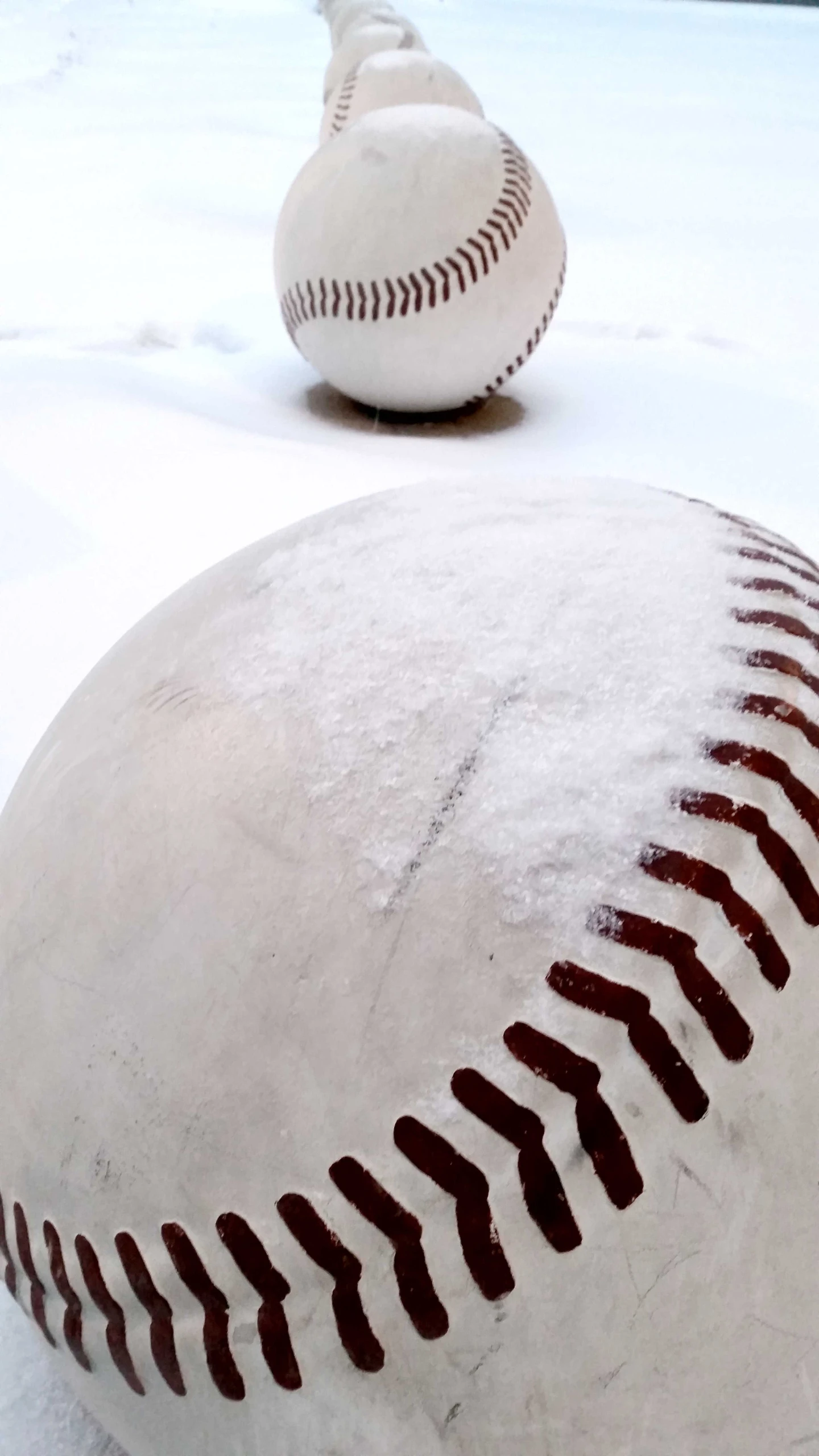 two baseballs that are covered in ice in the snow