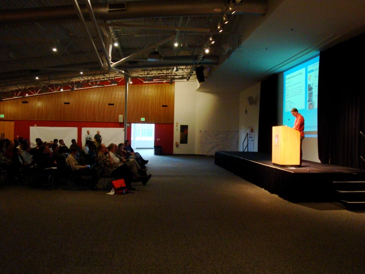 a woman is standing at the top of a stage and giving a presentation