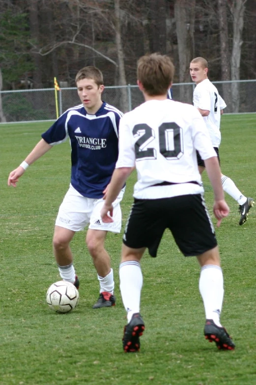 several young men playing soccer on a grassy field