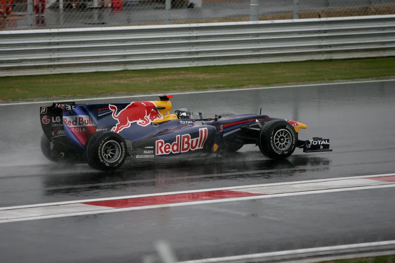 a red bull car driving through the rain