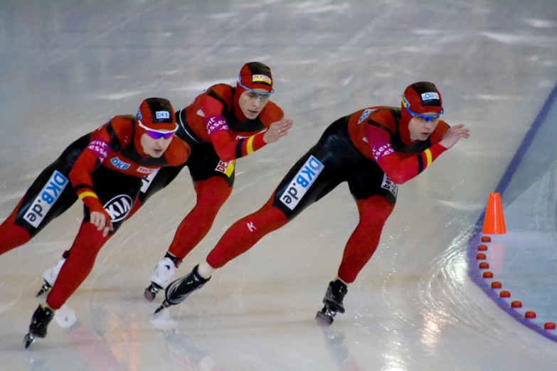 two men in red are competing in a speed skating competition