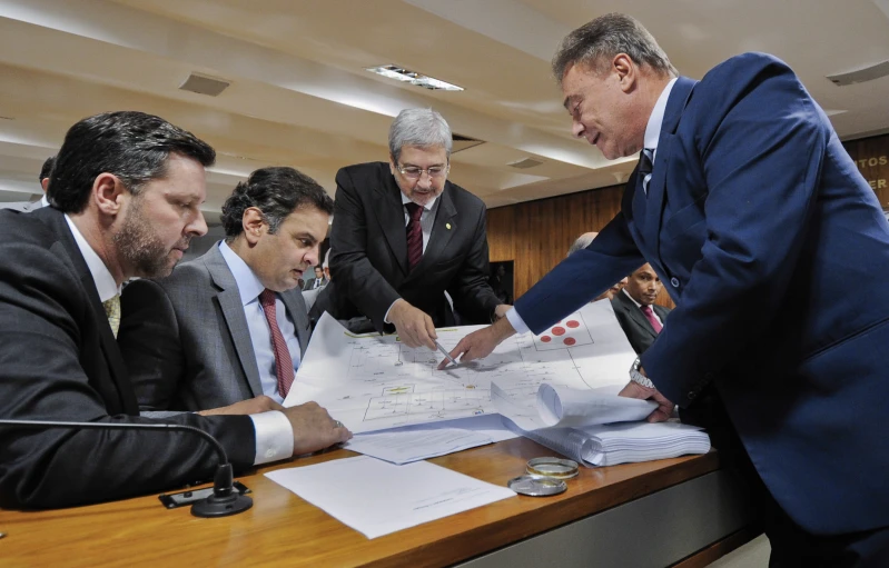 men looking at the contents of a plan in a meeting room