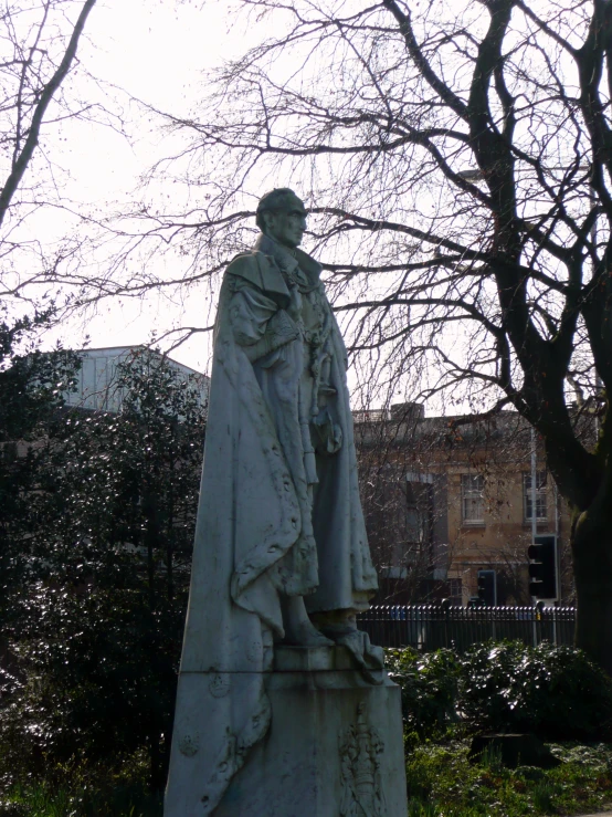 a statue of a man holding a cross stands in the center of a yard