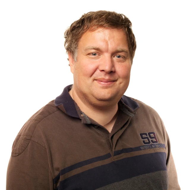 a smiling man wearing a brown shirt with blue stripes