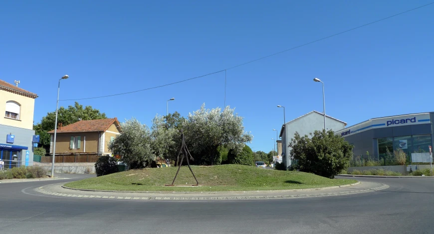 a small round roundabout with a house and trees