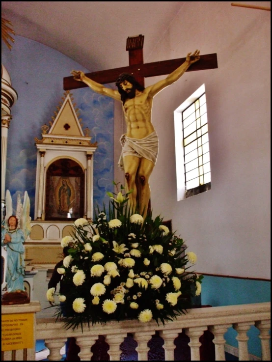 a man hanging on the cross above flowers