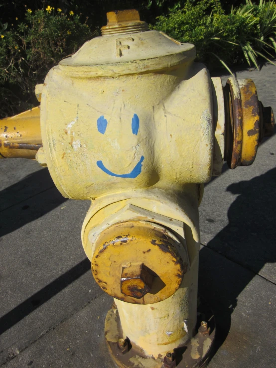 an old yellow fire hydrant with a face drawn on it