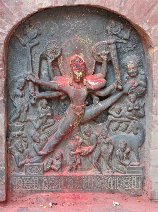 a sculpture of a hindu person on a brick wall