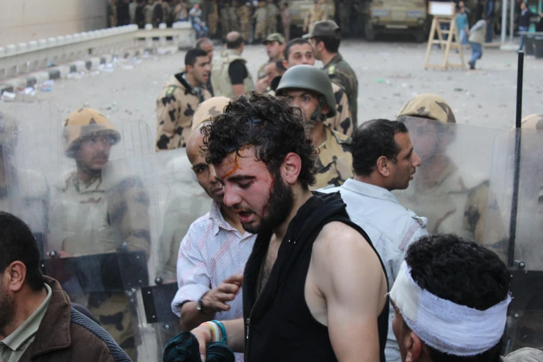 a man with paint on his face and beard, surrounded by other men