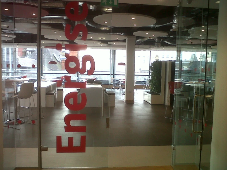 there is a building lobby with glass walls and red lettering