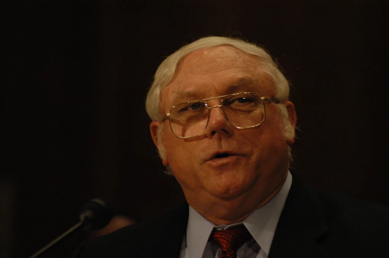 a man in glasses and a tie is giving a speech