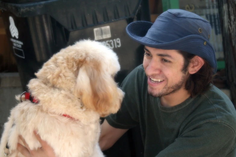 a man in a blue hat pets his dog