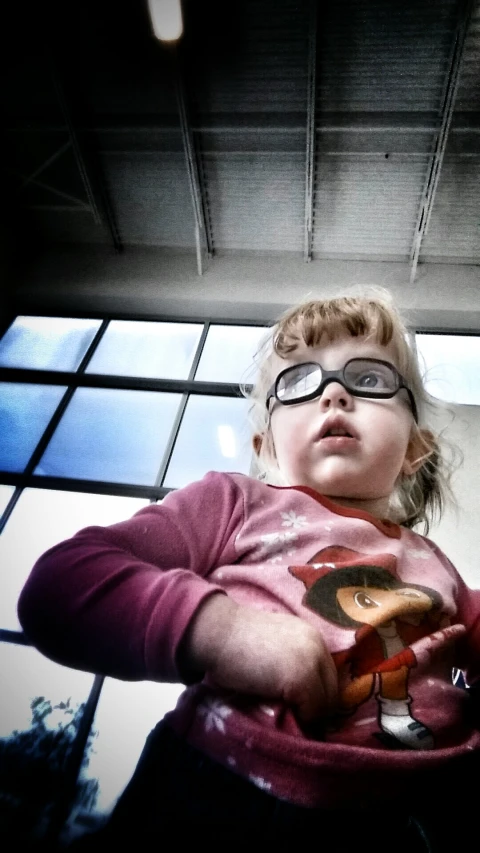 a little girl wearing glasses holding a cellphone