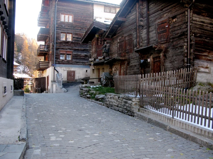 a cobblestone street has wooden buildings and wooden balconies