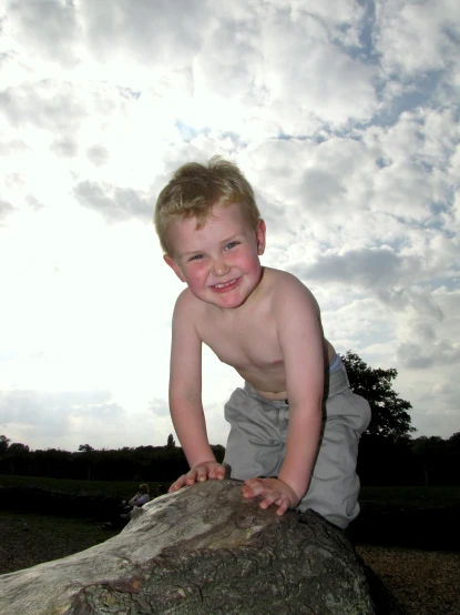 a young child sitting on a rock in a field