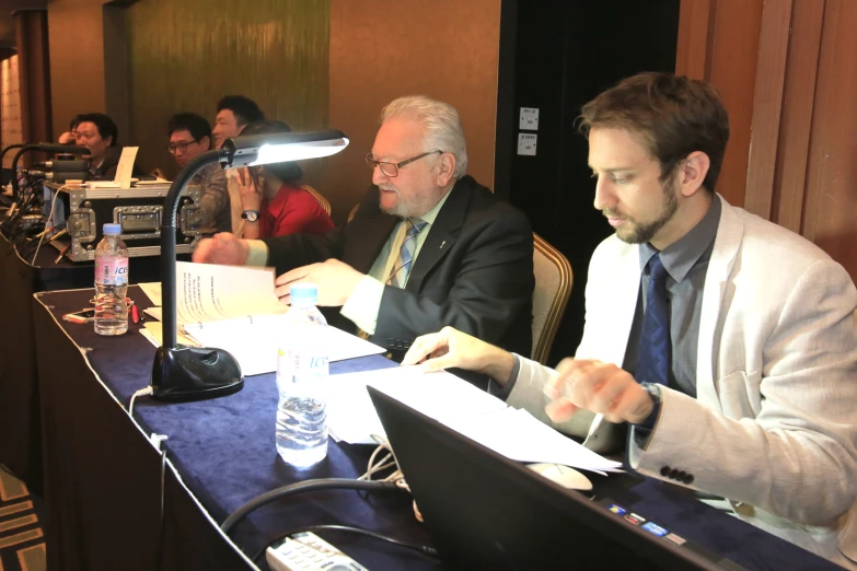 two men sitting at a table looking at papers