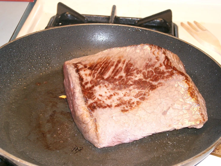 steak being prepared in pan on stove top