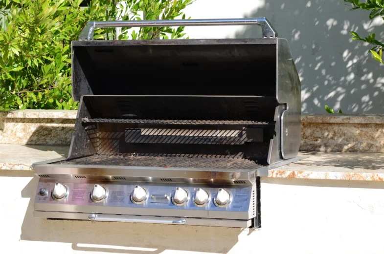 a metal barbecue grill sitting outside next to a wall