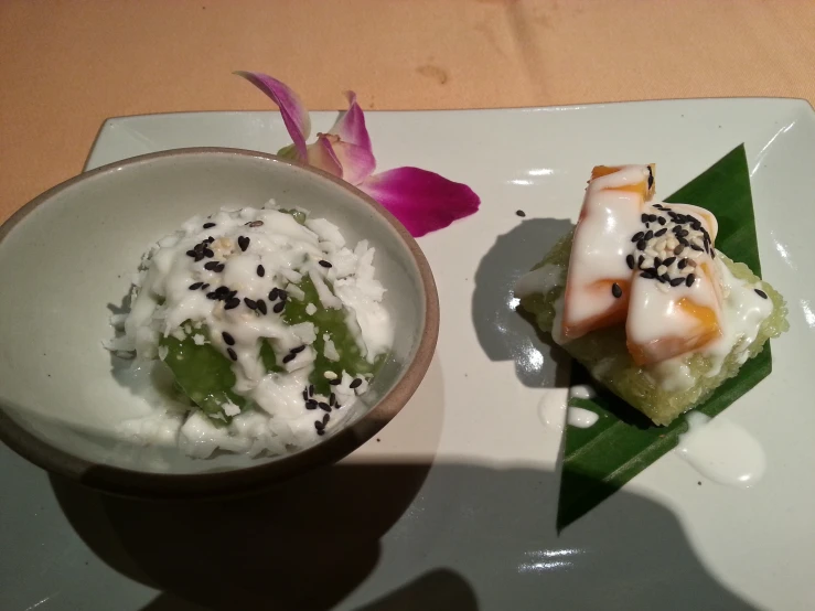 a white plate holding sushi and rice with sauce on it