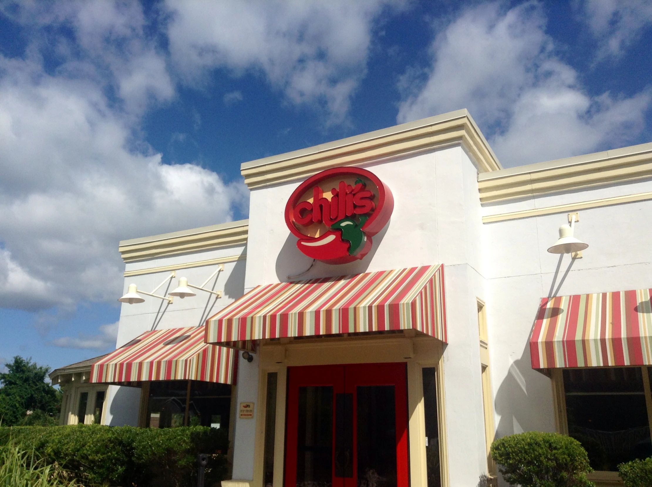 a storefront with awnings, striped awning and red door