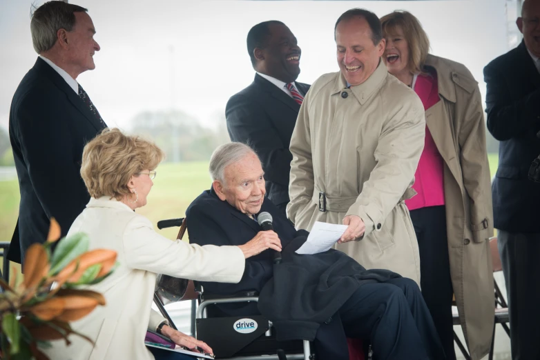 two adults talking to a woman in a wheelchair