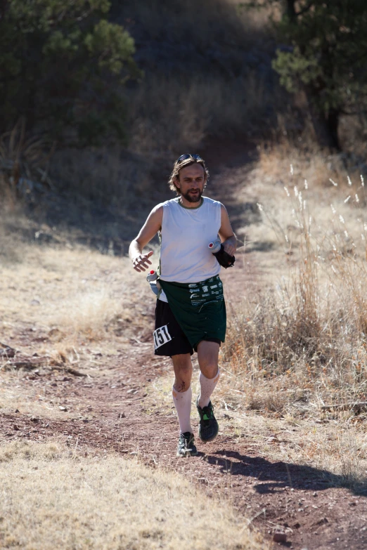 a man running in a trail with gloves on