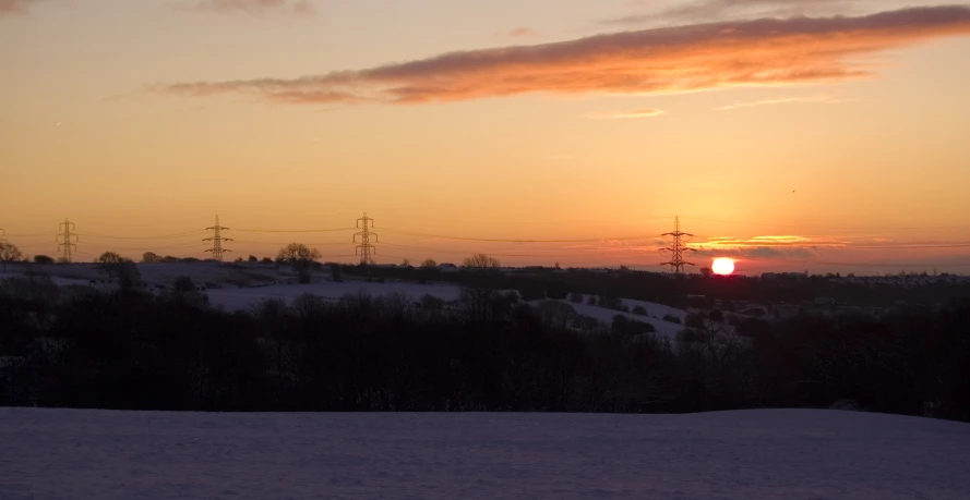 the sun sets over an area where telephone poles are located