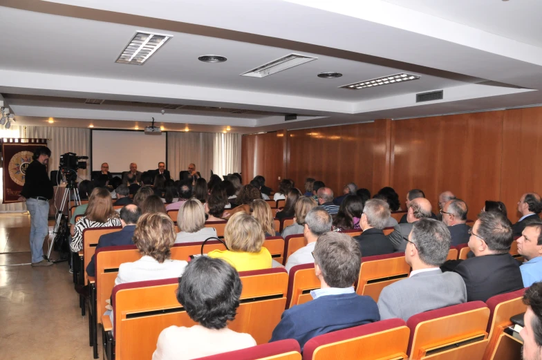 people standing in a room filled with red chairs