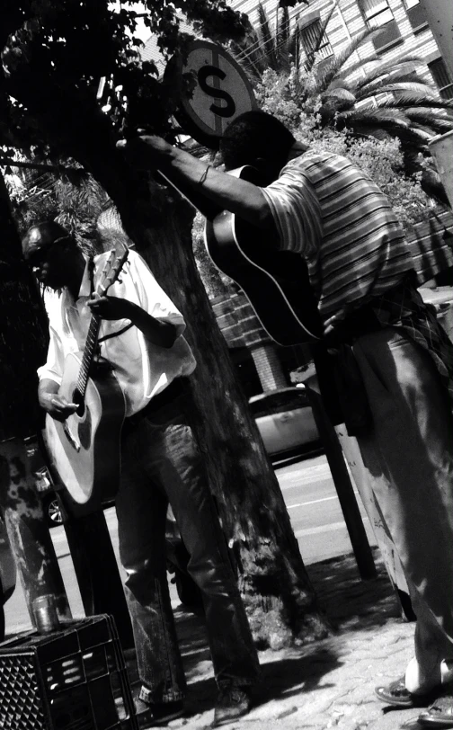 several men sitting and playing music in front of trees