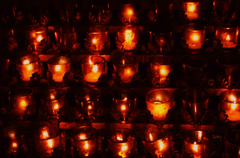 many lit candles sitting in front of the wall