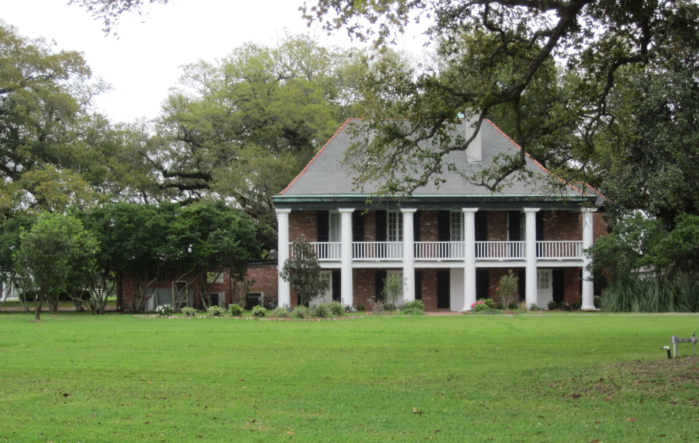 a large home with a covered patio sits on an expansive green field