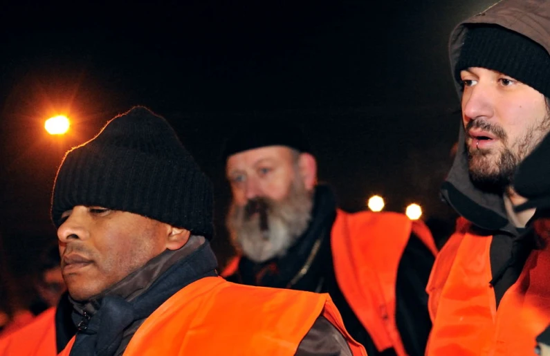 two men in orange vests and black hats