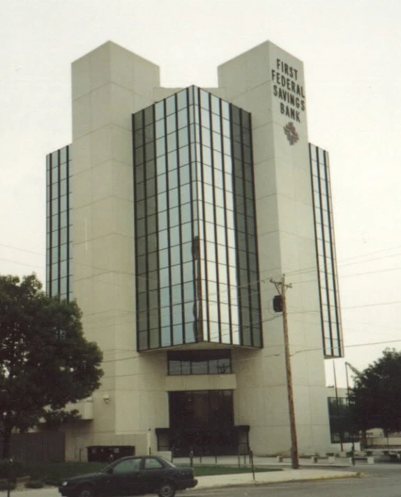 a car driving past an office building with two very tall buildings