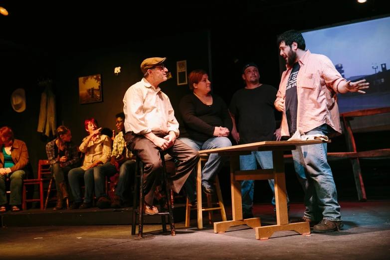 three people sitting at a table talking to two men