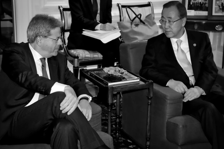 two men sitting in chairs with papers on the floor