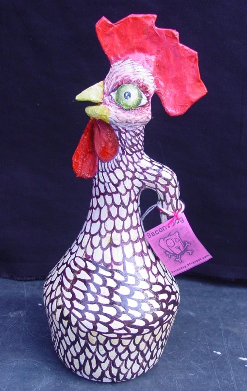 a decorative ceramic rooster with a tag in its'beak