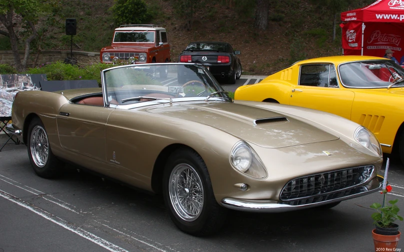 a tan and black car sits parked beside another yellow car